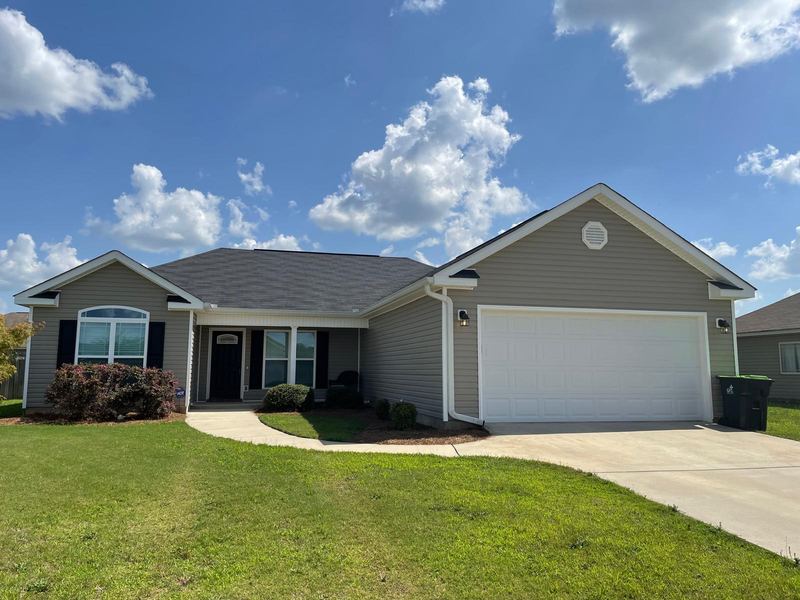 Single-story home with gray siding, black shutters and a two-car garage, under a blue sky.