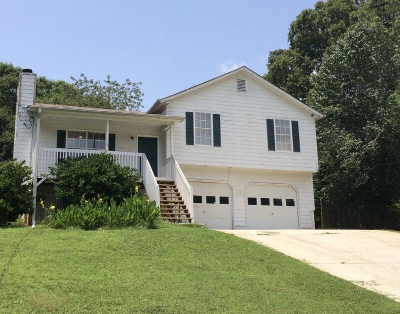 White split-level home with a front porch, wooden stairs and a two-car garage.